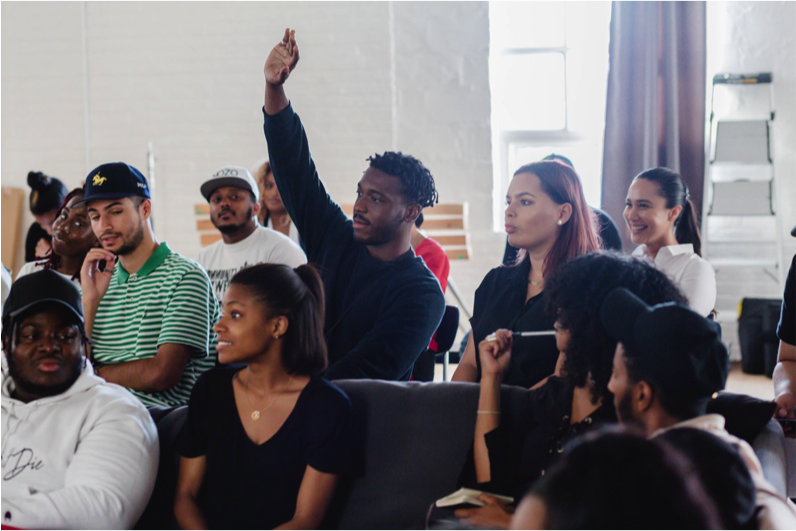 Un étudiant lève la main dans une classe de participants au projet Remix.